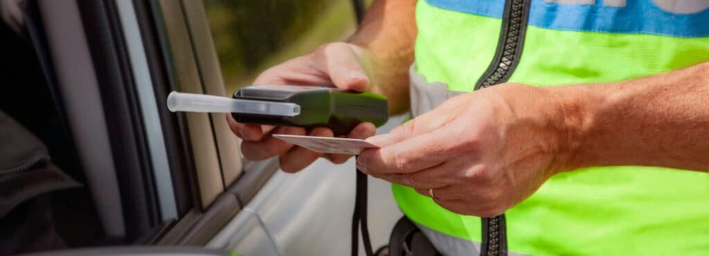 Police officer administers a breath test to a driver during a DUI investigation