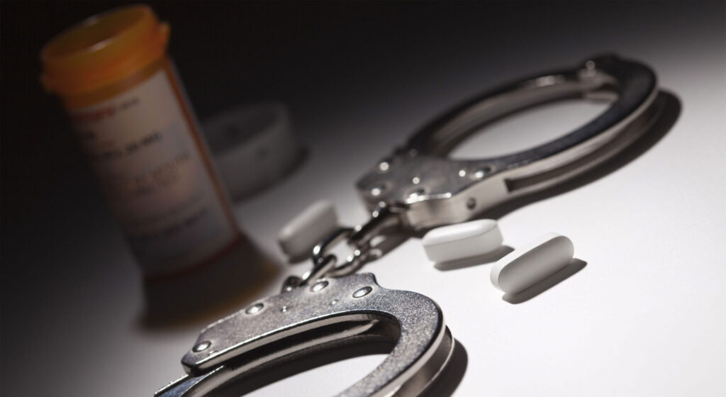 Handcuffs and prescription pill bottle on a table